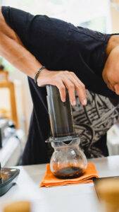 Someone squeezing Aeropress Coffee into a jug, on the top of Bean Merchant's how to make Aeropress Coffee website